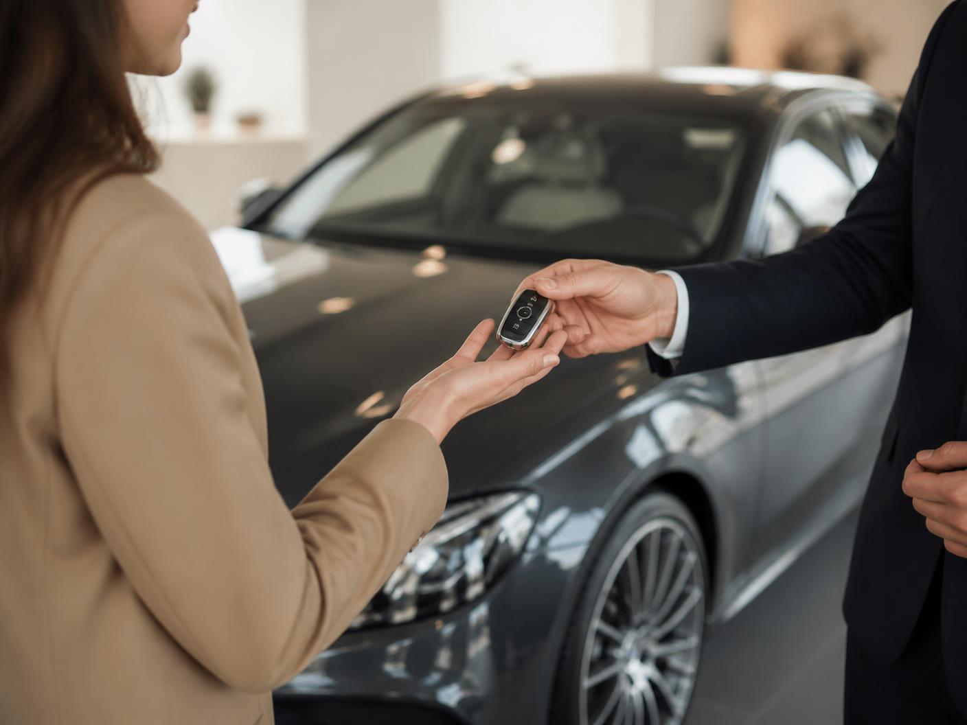 Entrega de chave de viatura premium a cliente em showroom claro